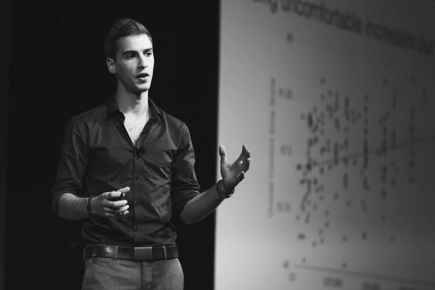 Portrait of Marcus speaking at a marketing event with a trend chart in the background.
